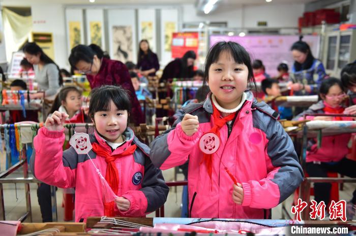 圖為小學(xué)生展示繡制好的2022年北京冬奧會吉祥物“冰墩墩”形象?！∮髟屏?攝