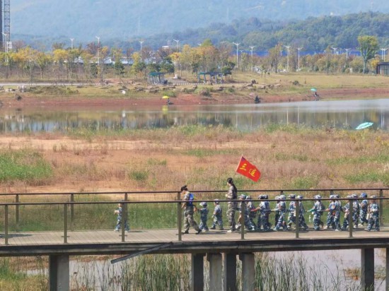 　　10月24日，秋游的幼兒園小朋友在老師帶領下走在清水塘公園里的木橋上。本報記者 常雯宜攝