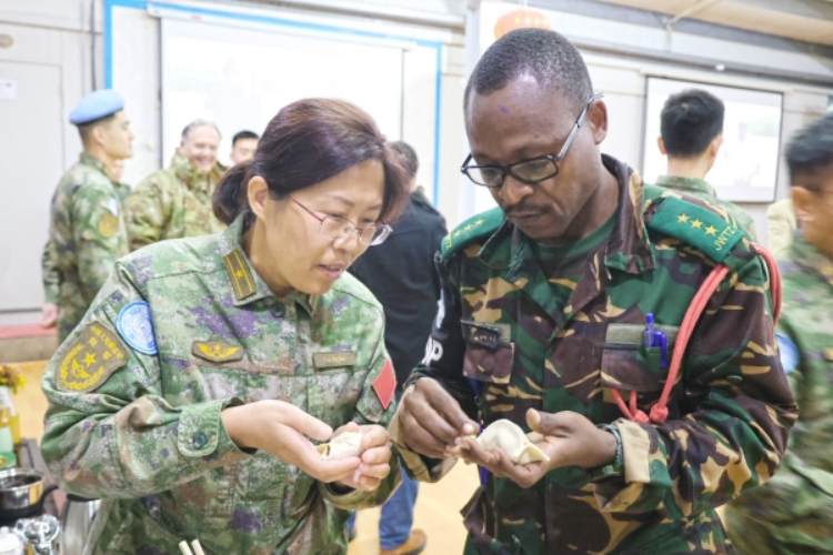 圖為維和官兵與外軍人員共同包餃子。胡光明攝