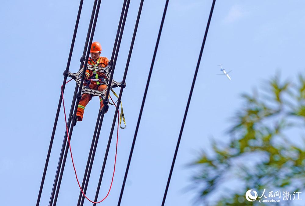 3月11日，在浙江省諸暨市河上鎮(zhèn)，浙江省送變電工程有限公司檢修人員在高空的導(dǎo)線上進(jìn)行線路檢修維護(hù)。人民網(wǎng) 章勇濤攝