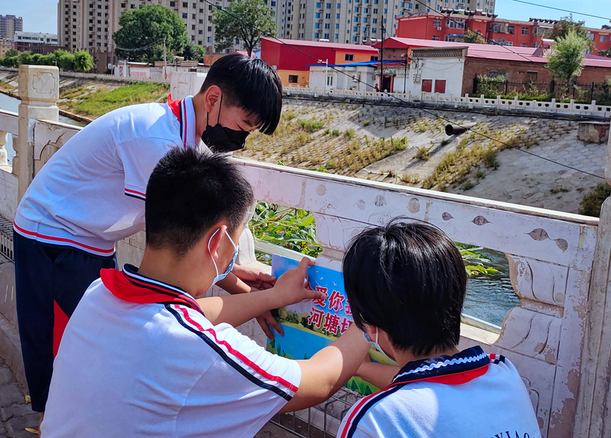 徐水小學(xué)學(xué)雷鋒志愿者在瀑河河邊張貼防溺水警示標(biāo)語(yǔ)。 徐水區(qū)委宣傳部供圖