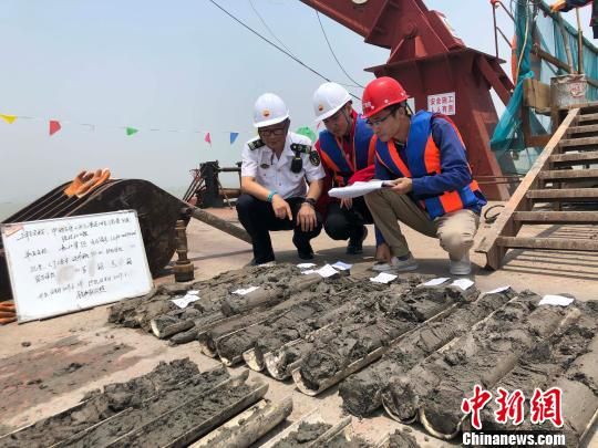 圖為勘察設(shè)計人員與海事局工作人員查看巖芯情況?！∥赫?攝
