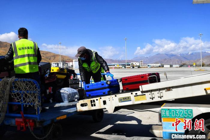 圖為機(jī)場工作人員傳送旅客行李箱?！≈芎?攝