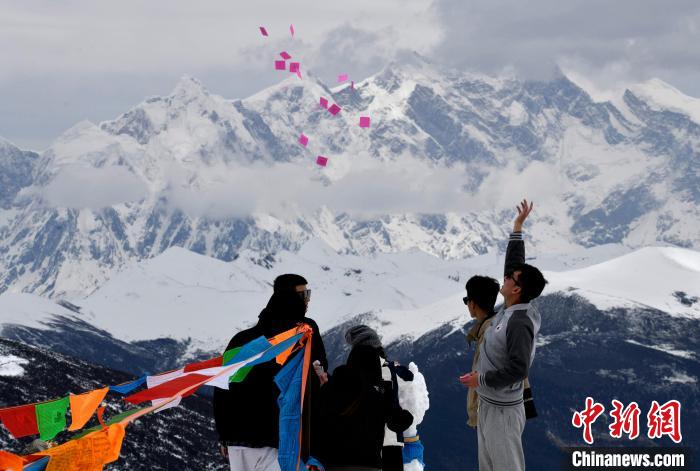 圖為5月14日，游客在西藏林芝色季拉山觀景臺(tái)拋灑“隆達(dá)”(風(fēng)馬旗，藏族民眾的一種祈福方式)?！±盍?攝