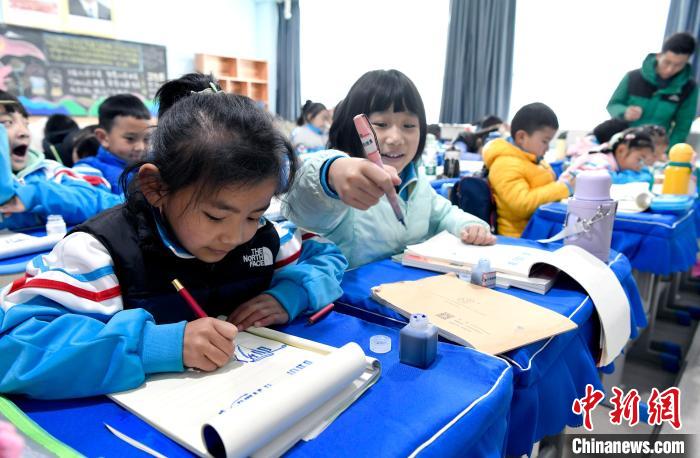 3月14日，西藏拉薩市第一小學(xué)一年級(jí)六班學(xué)生白瑪朗珍(圖左)在藏語文課上書寫藏文。　李林 攝