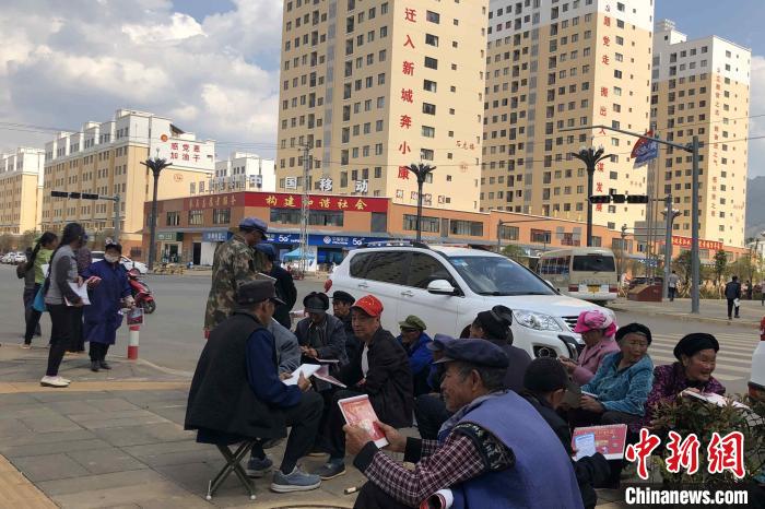 圖為會澤縣城易地扶貧搬遷安置點內(nèi)，老人們聚在廣場上聊天，身后是他們的新家?！】姵?攝