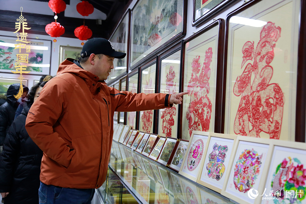 2025年1月23日，游客在天津楊柳青古鎮(zhèn)欣賞傳統剪紙作品，感受指尖上的古老藝術。人民網記者 崔新耀攝